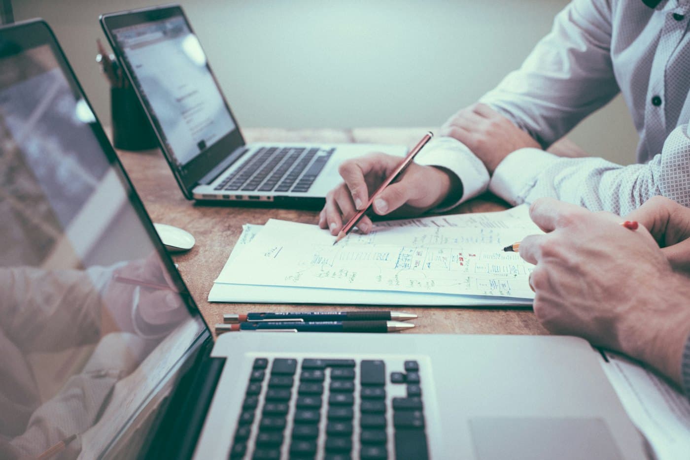 Hands reviewing a working file at a desk — HR that stays attached after arrival.