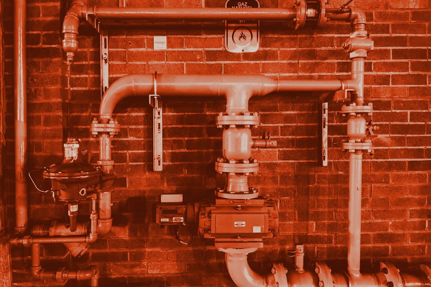 Site plumbing and pipework on a brick wall.